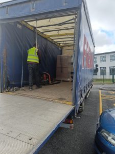 the open back of a delivery truck with large boxes being unloaded by a person in a high vis vest