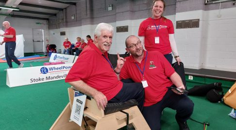 2 smiling participants, one of whom is sitting in the Sword Seat, and Coach Alice wearing red WheelPower t-shirts, clearly having a great time.