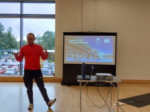 Ben Quilter from ParalympicsGB presenting about the Discover days in front of a screen at the Discover Day NGB networking session.