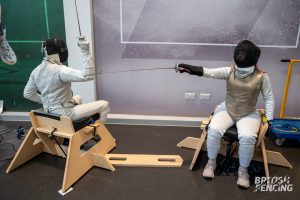 Two fencers checking distance sitting in the sword seat ready to start a bout