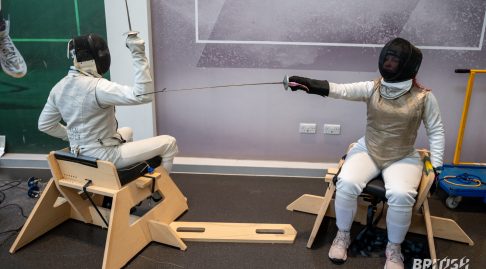 Two fencers checking distance sitting in the sword seat ready to start a bout