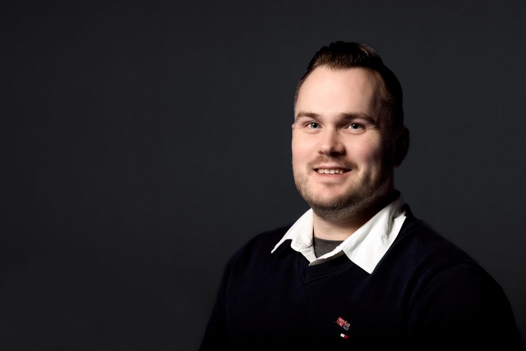 An image of Rick smiling to the camera wearing smart clothing and a British Fencing logo pin. 